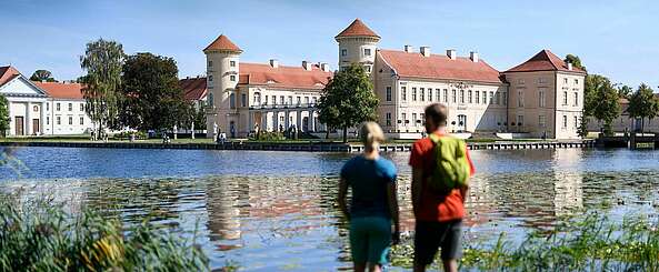 Besucher am Ufer des Grienericksees vor dem Schloss Rheinsberg